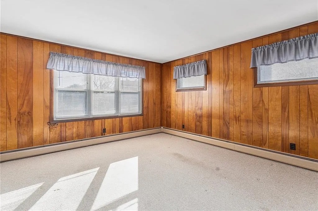 Dated room with wood paneling and worn carpet before renovation