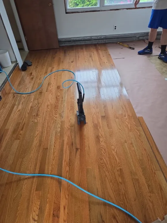 Hardwood floor refinishing in progress with a finished section visible