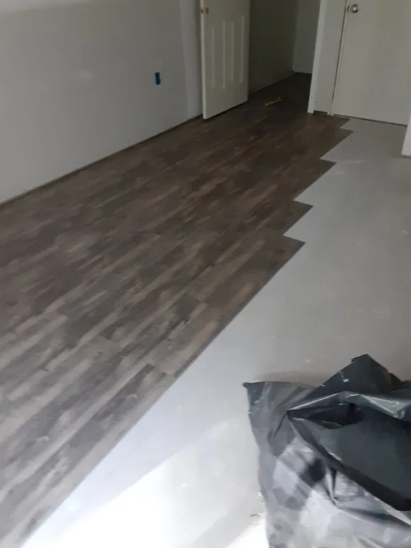 Wood-look plank flooring installation progressing across a bedroom