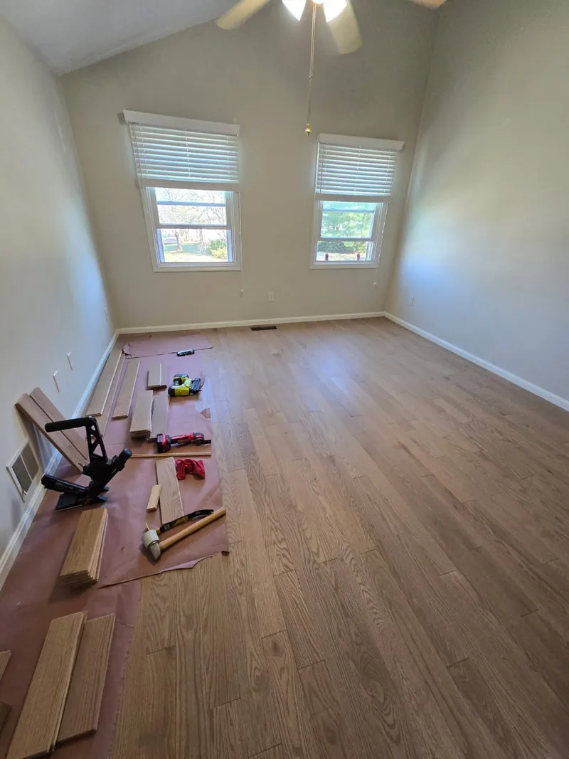 White oak hardwood installation with tools staged along the edge of a vaulted bedroom