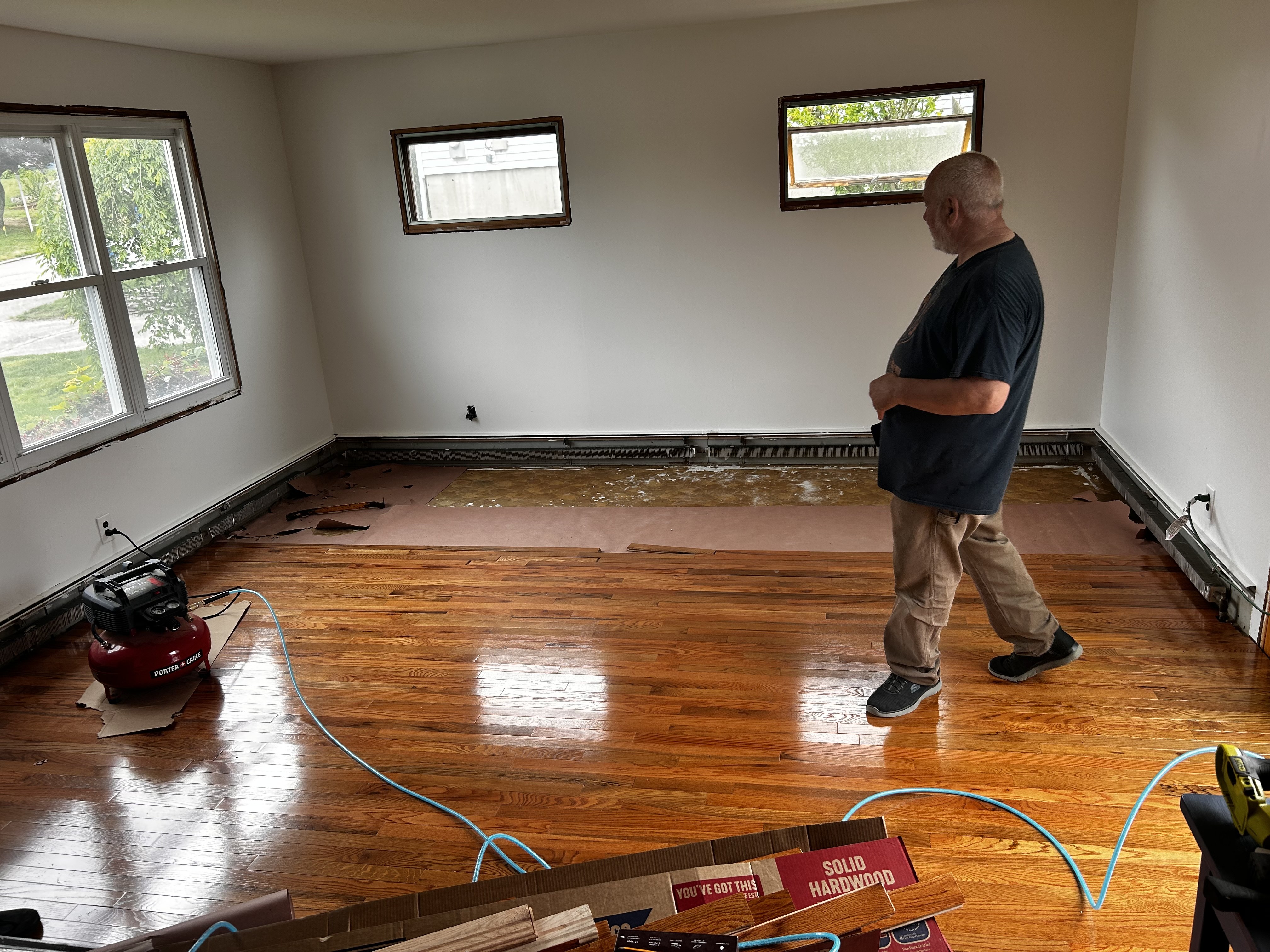 Cook Flooring craftsman standing over a glossy amber hardwood floor during installation